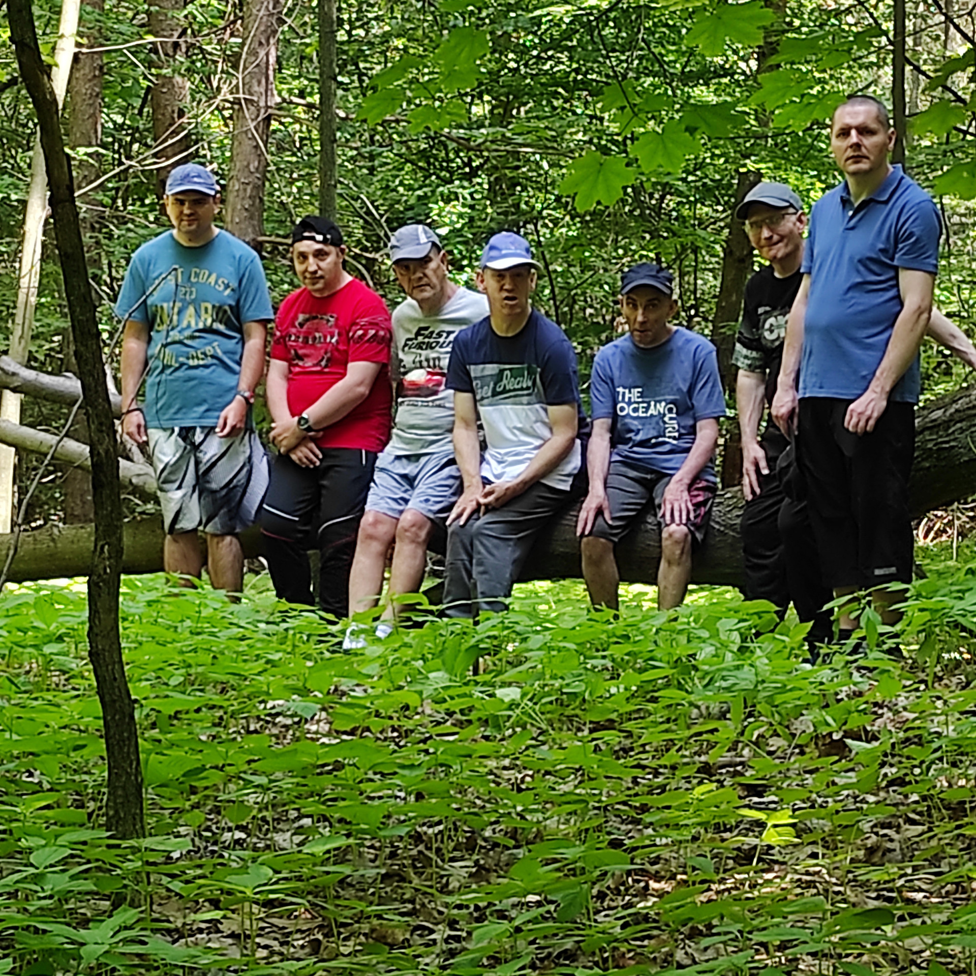 Zdjęcie grupowe, na którym siedmiu podopiecznych opiera się o leżące leśne drzewo.