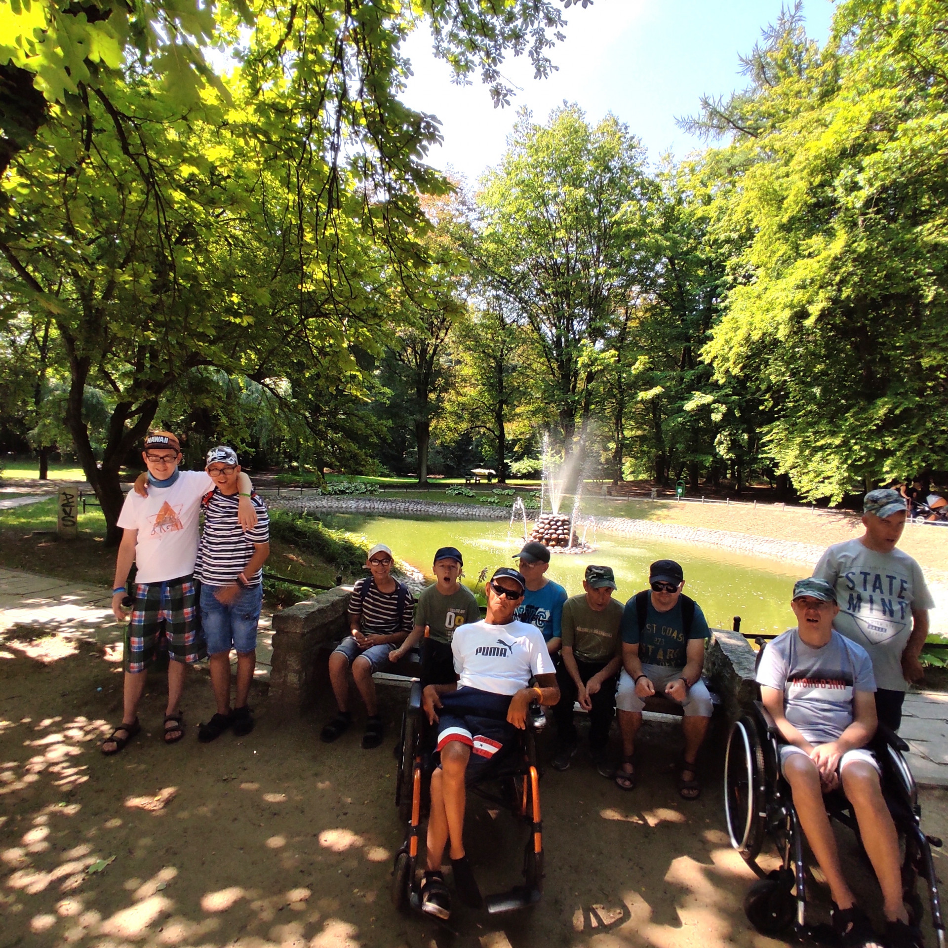 Grupa gromadzi się przed stawem z fontanną.