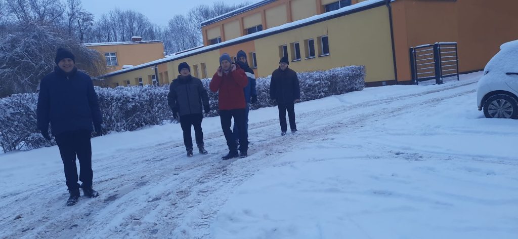 Pięciu mieszkańców stoi przed zabudowaniami  Zespołu Szkół Centrum Kształcenia Rolniczego w Nakle Śląskim. Widać śnieg.